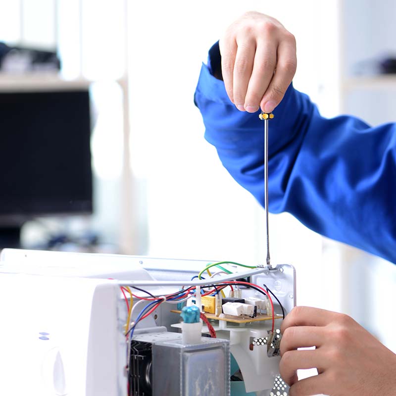 The young repairman fixing and repairing microwave oven